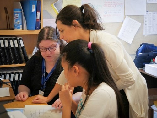 Two teachers of students with visual impairments and one student examine the accessible coding materials