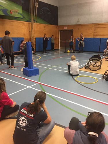 Photo shows teachers demonstrating an adaptive sport in a gymnasium