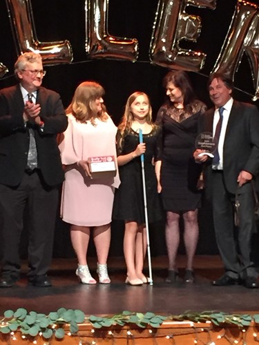 Image shows a student on stage to receive a second place award at the Braille Challenge