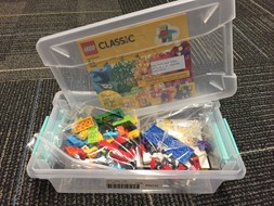 Photo shows a plastic bin with braille lables and LEGO