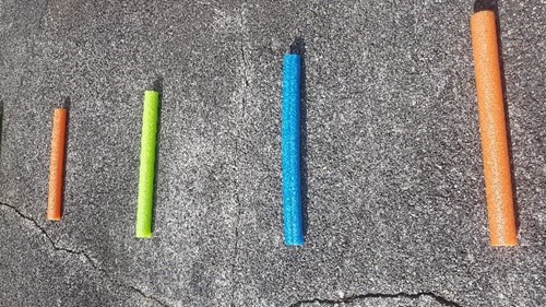 Segments of pool noodle of warying lengths are set out on the sidewalk