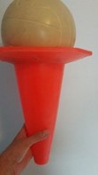 An orange traffic cone held upside with a ball supported in the base